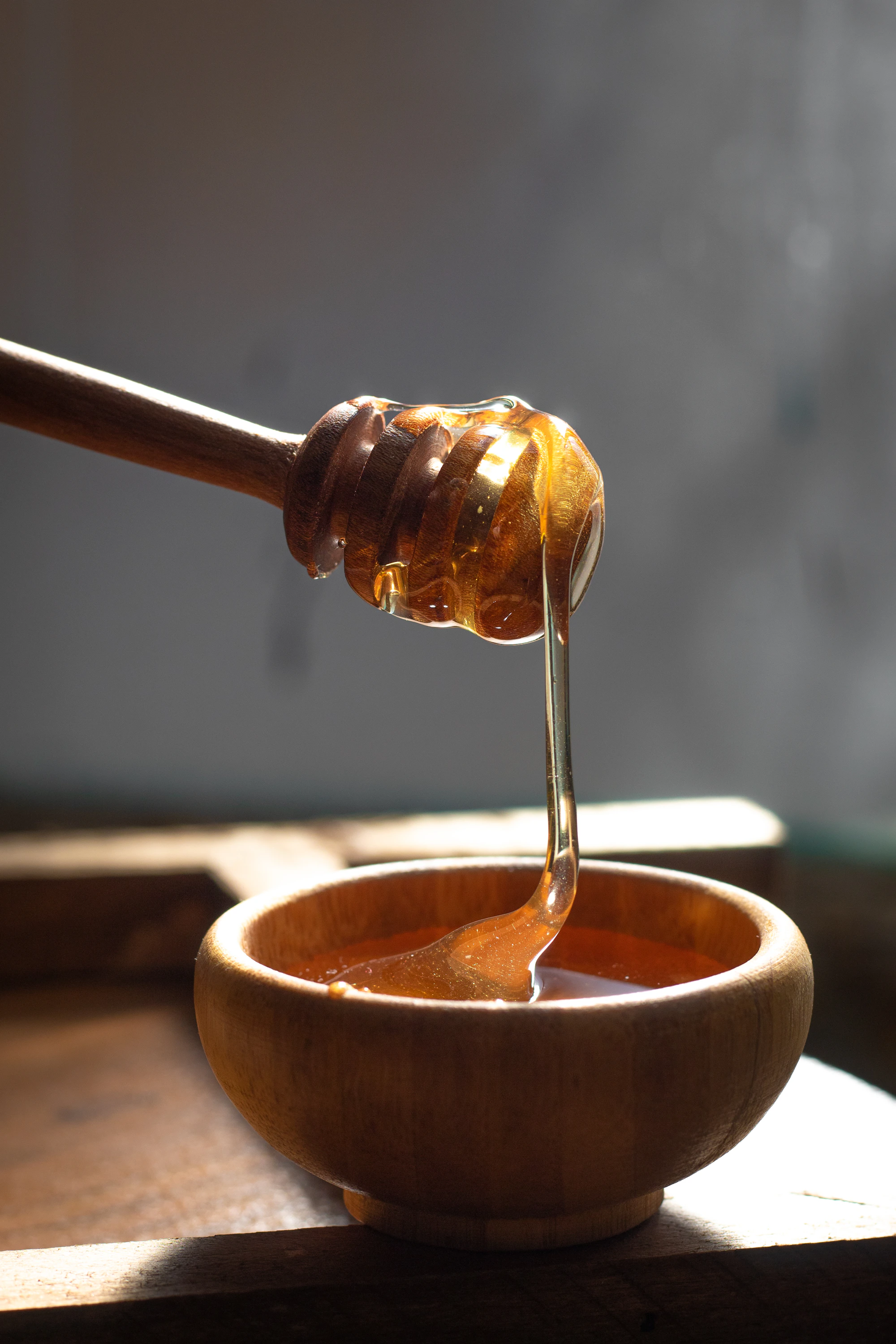 蜂蜜从木制蜜棒缓缓流入木碗